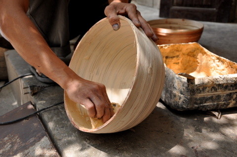   L'artisan enduit l'objet d'un mastic qui permet l’étanchéité entre les lamelles de bambou.
