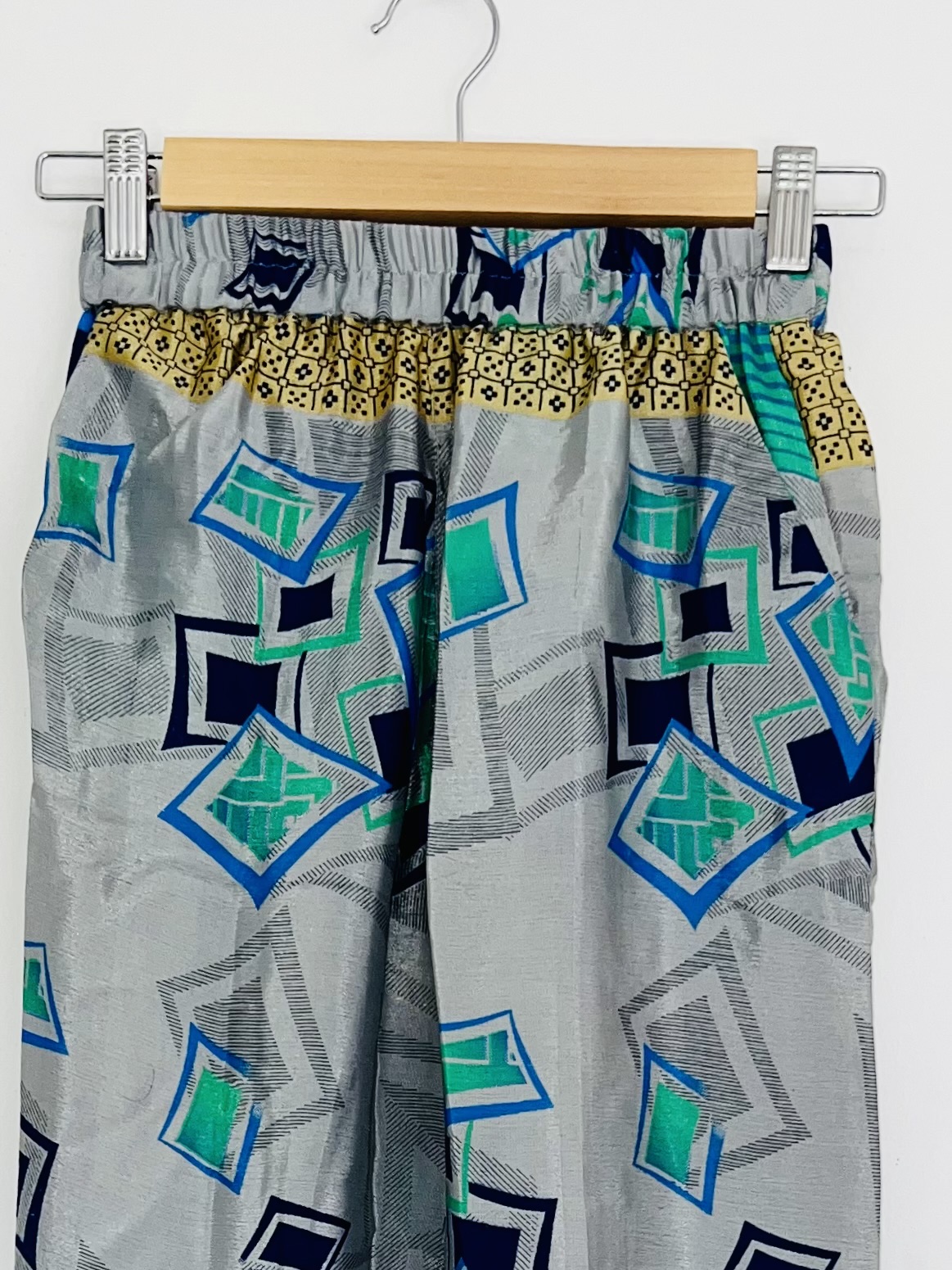 Détail du haut – Motifs asymétriques noirs et verts sur fond gris