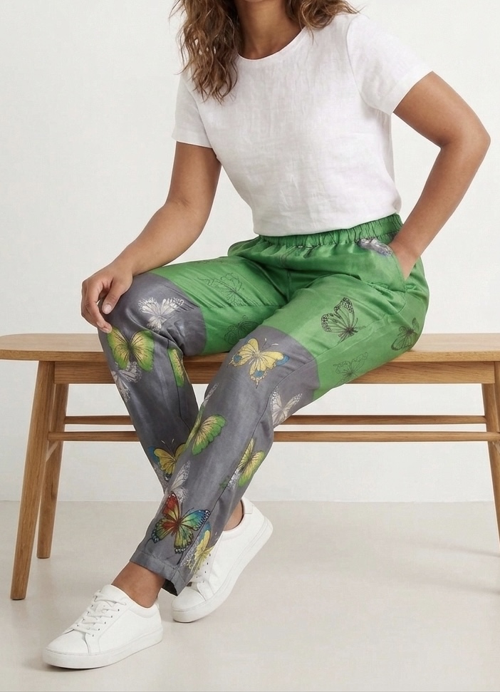 Mannequin assis sur un banc portant pantalon vert vif et gris souris en sari recyclé avec papillons noirs sur le haut et papillons colorés sur le bas
