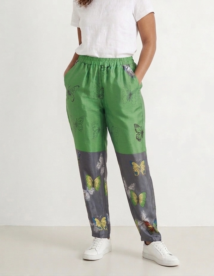 Mannequin debout avec les mains dans les poches portant pantalon vert vif et gris souris en sari recyclé avec motifs de papillons