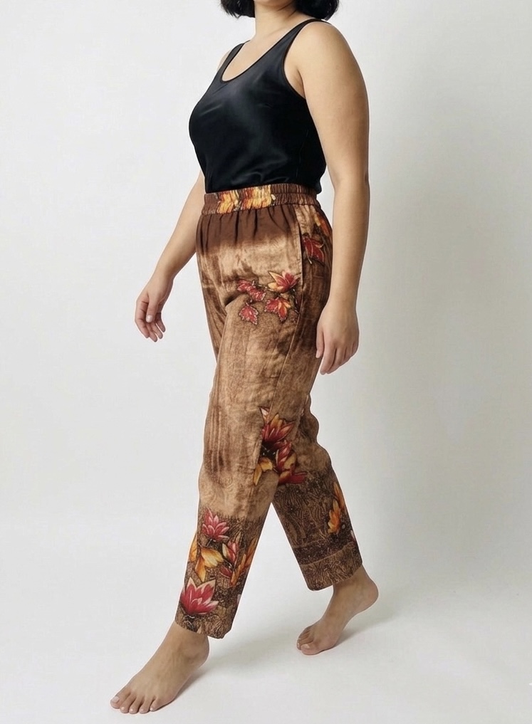 Mannequin marchant portant pantalon marron et beige en sari recyclé avec grandes fleurs jaunes et roses et inscriptions indiennes