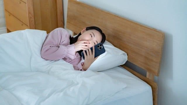 深夜までスマートフォンを見る女性