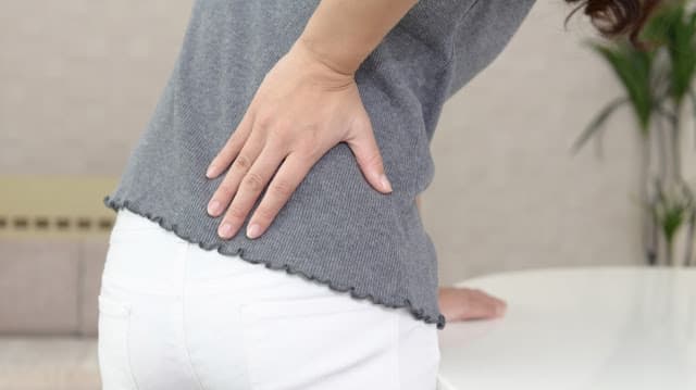 腰痛で腰をおさえてる女性