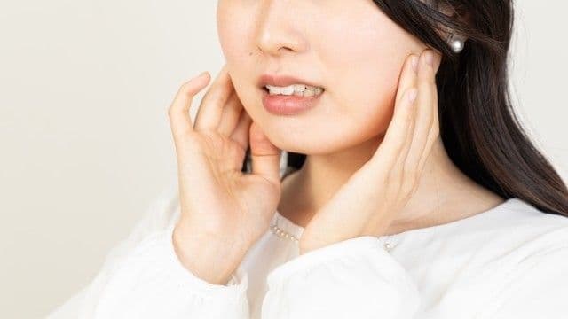 顎の下を押さえる女性(食いしばりによる頭痛)
