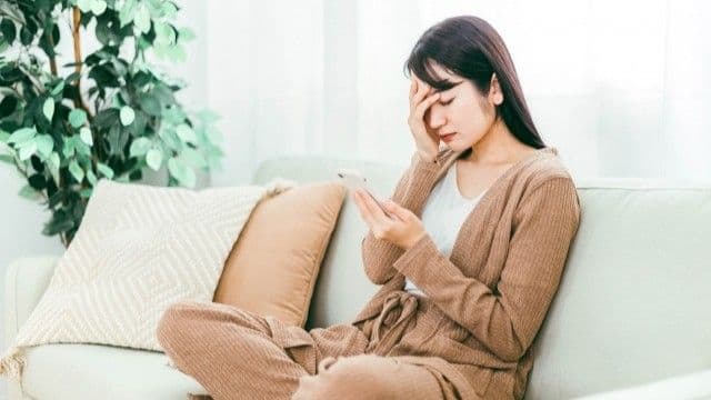 眼精疲労による頭痛で頭と目の周りを押さえる女性
