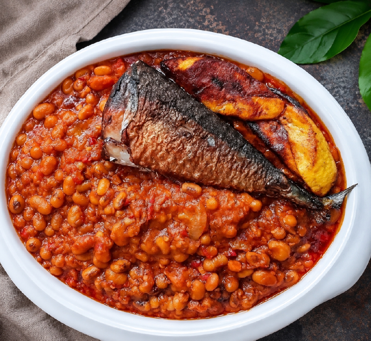 Delicious Nigerian Beans Porridge with Smoked Fish & Fried Plantain Savor the rich taste of perfectly cooked beans porridge, served with flavorful smoked fish and golden fried plantains. A nutritious, satisfying meal prepared with authentic Nigerian ingredients and traditional recipes.
