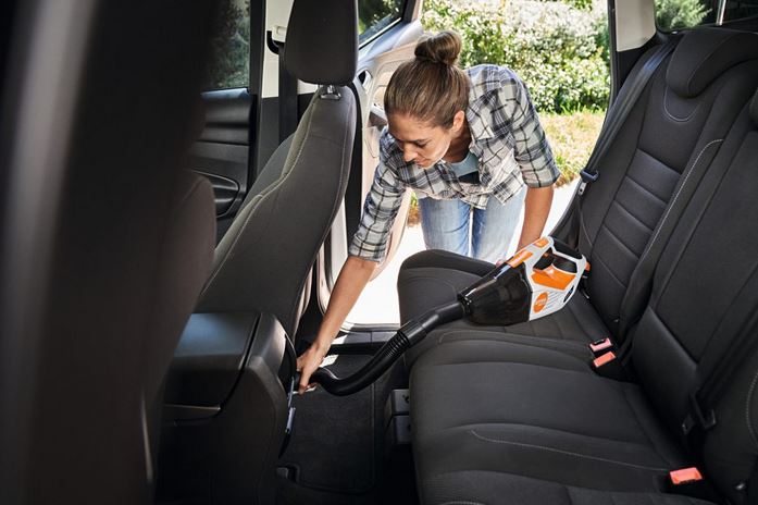 Frau am Autos reinigen mit Staubsauger stihl