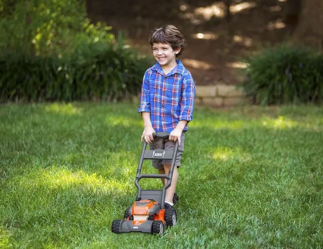 Kind am Rasenmähen mit Spielzeug Rasenmäher