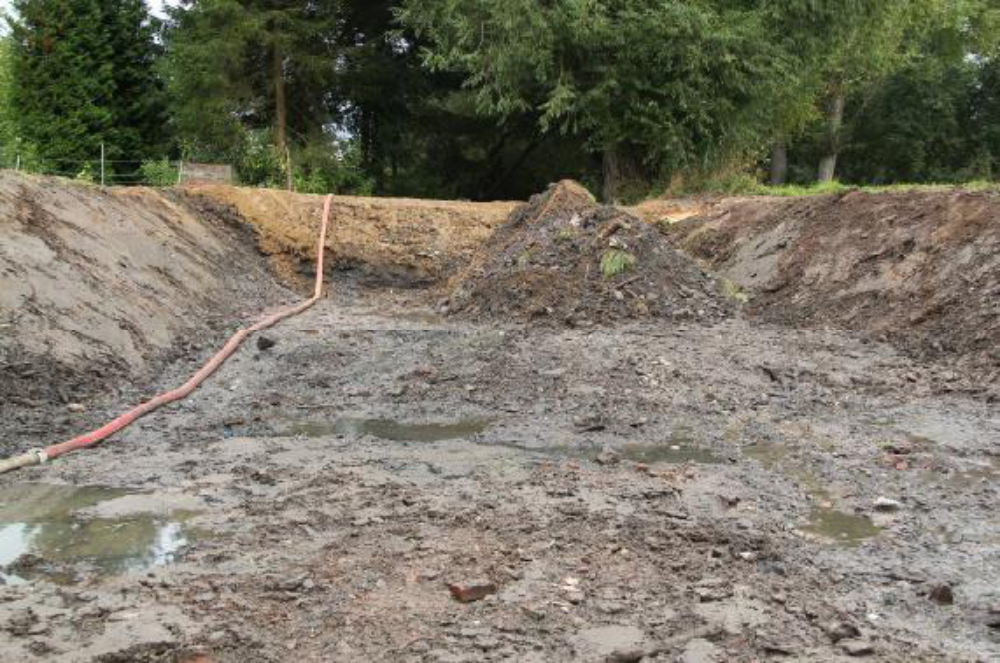 Eine Tauchpumpe hält im frei geräumten Kolk den Grundwasserspiegel flach. Der Damm wurde noch einmal erhöht, weil sich durch Setzungen die Krone abgesenkt hatte.