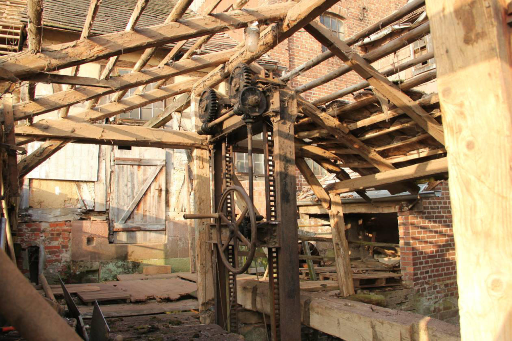 Der offene Wehrgang. Hinten rechts die Turbinenkammer mit ausgebautem Läufer. Die Tür in der Mitte führt direkt in die Mühle. Die Vorteile eines Dachs schätzt man spätestens wenn bei Hochwasser das frei stehende Wehr bedient werden muss. 