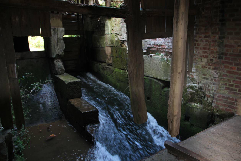 Links die alte Wasserradanlage. Im Leerschuss sind die Schützentafeln angehoben. Zwischen oberer und unterer Tafel ist systembedingt ein Spalt entstanden. Bei Betreten Lebensgefahr! Hier hängt der Rest der Wand am Dach. 