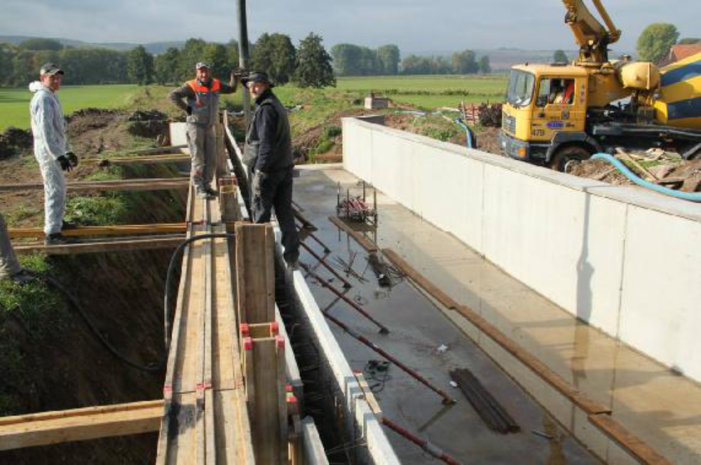 Betonieren der rechten Trogwand. Die linke Wand ist bereits ausgehärtet und steht frei. Weil dahinter mal eine Terrasse angelegt werden soll, hat die Wand oben eine Abschlusskante. Aufgenommen am 9.10.12