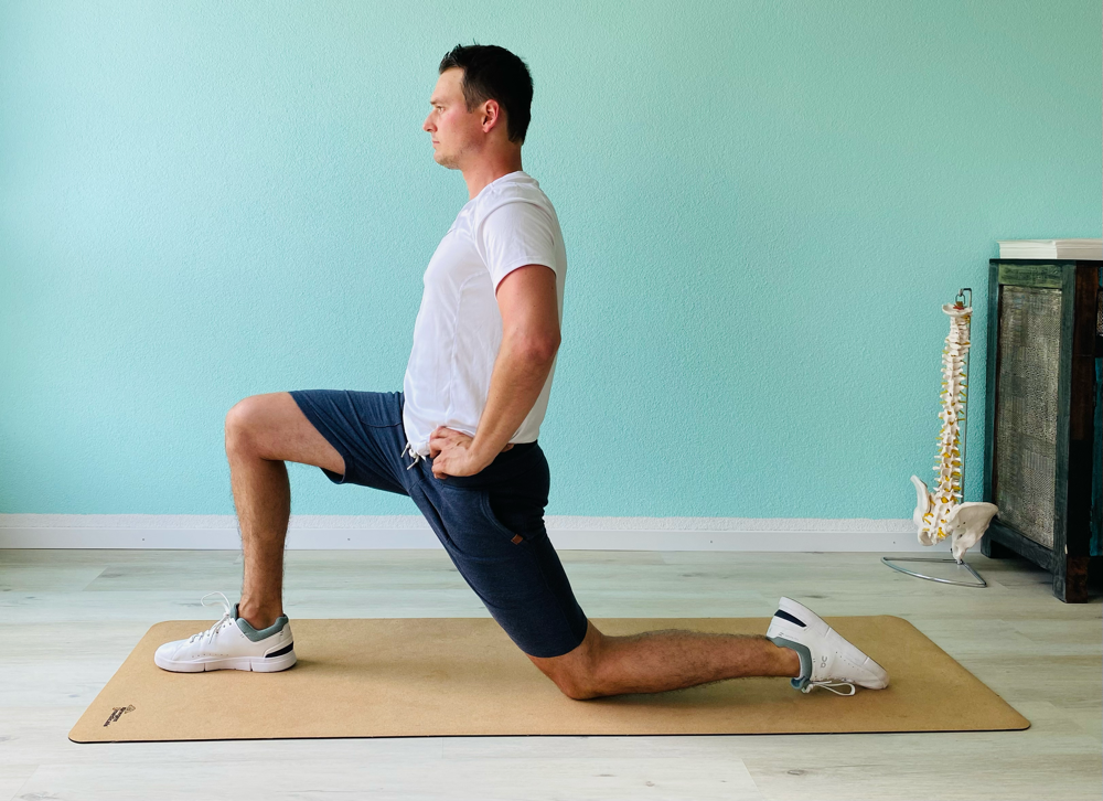 Psoas-Dehnung, Schambein zu sich ziehen, in Dehnung sinken, 90° Winkel bei vorderem Knie, Wirbelsäule aufwärts, Atmen.