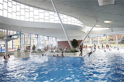 Hallenbad von Innen mit vielen Besuchern und einem Sprungturm
