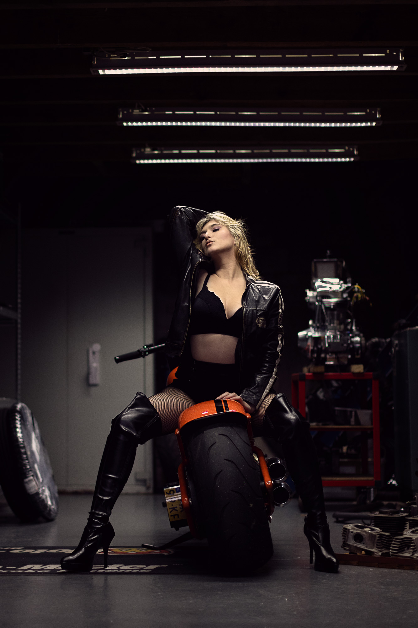 Stoere boudoirfoto van een motorrijdster op een harley davidson in garage 'wingpalace' in uden