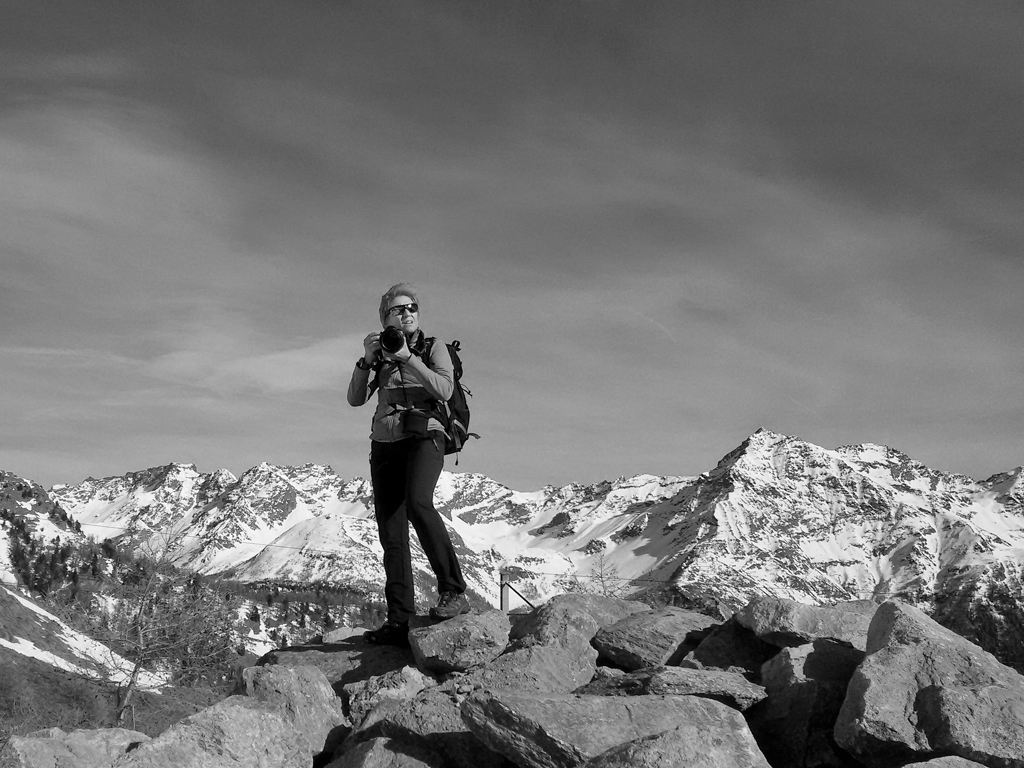 Black and white photograph of the photographer with the snow-covered Alps in the background