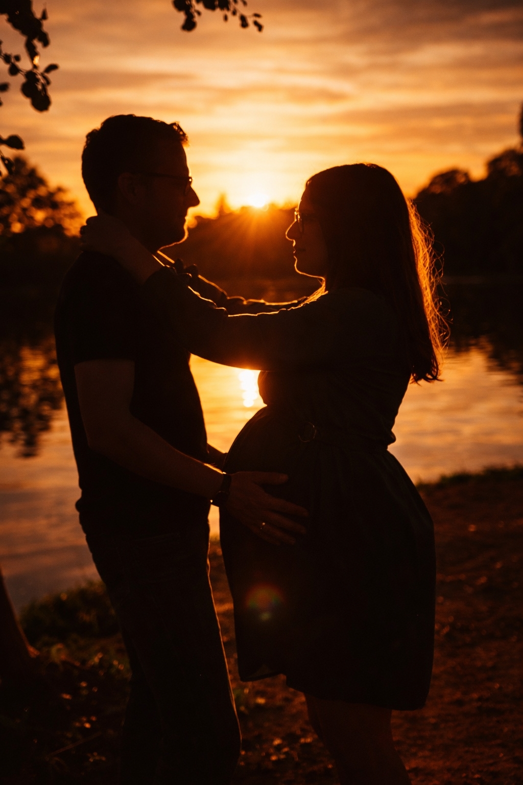 Babybauchshooting bei Sonnenuntergang am See im Werra-Meißner-Kreis – Silhouette eines Paares mit Schwangerschaftsbauch