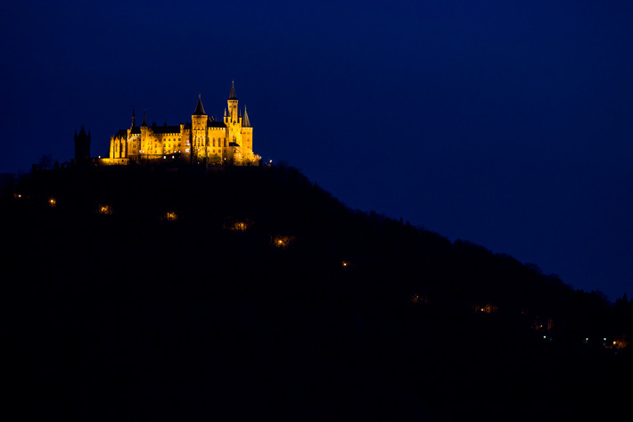 Blaue Stunde: Burg mit beleuchteter Auffahrt.