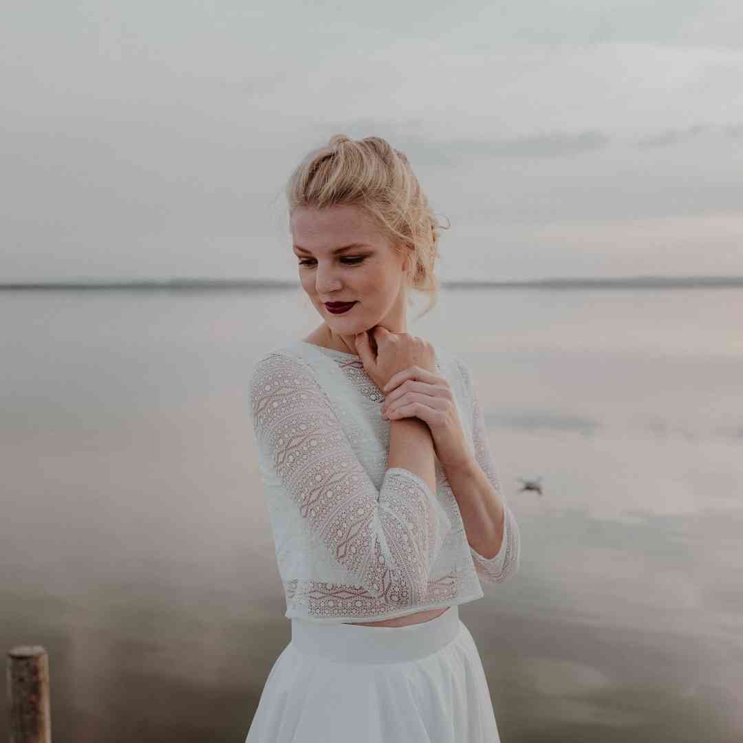 Braut-Zweiteiler im natürlichen Look → Braut trägt einen modernen Zweiteiler mit kurzem Top und fließendem Rock – perfekt für standesamtliche Trauungen.
