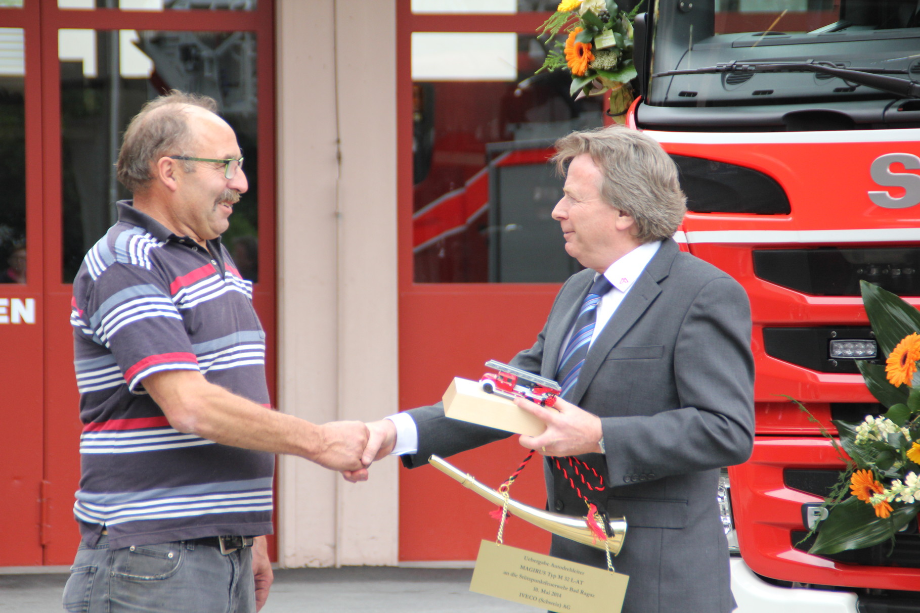 Hanspeter Sauter, Vertreter der Firma Magirus, gratuliert dem Feuerwehrverein Bad Ragaz zum 150-Jahr Jubiläum und überreicht dem Vereinspräsidenten "Särri" Sepp Widrig ein Präsent.