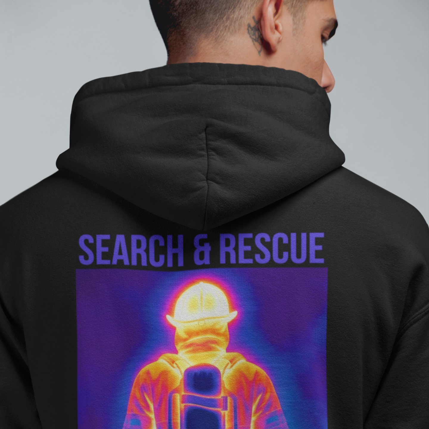 Nahaufnahme des Rückenprints auf einem schwarzen Hoodie mit der lila Aufschrift „SEARCH & RESCUE“ über einer bunten Wärmebild-Grafik.