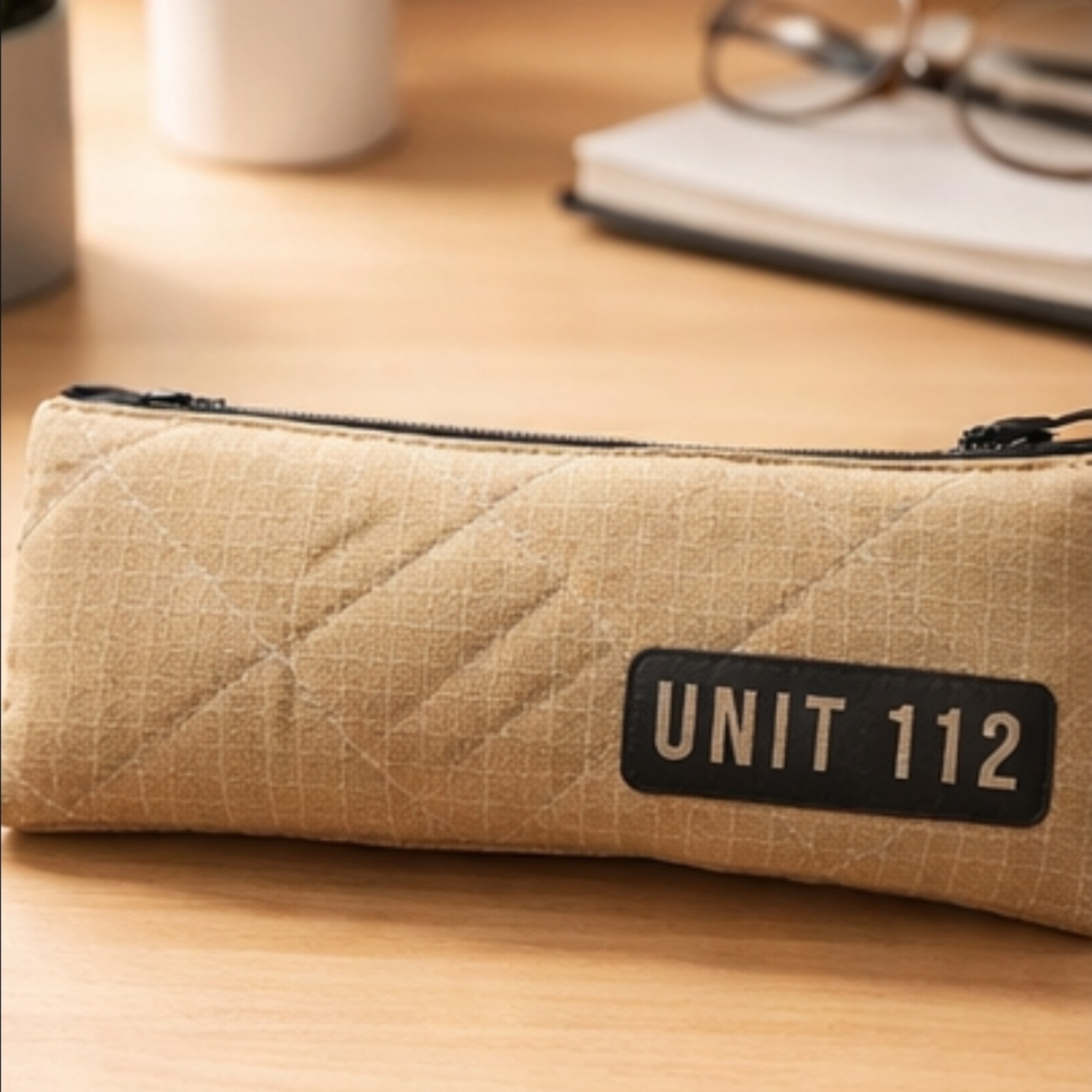 Kleine Tasche aus beigen Feuerwehrstoff, gesteppt mit einem Aufdruck "Unit112" in schwarz