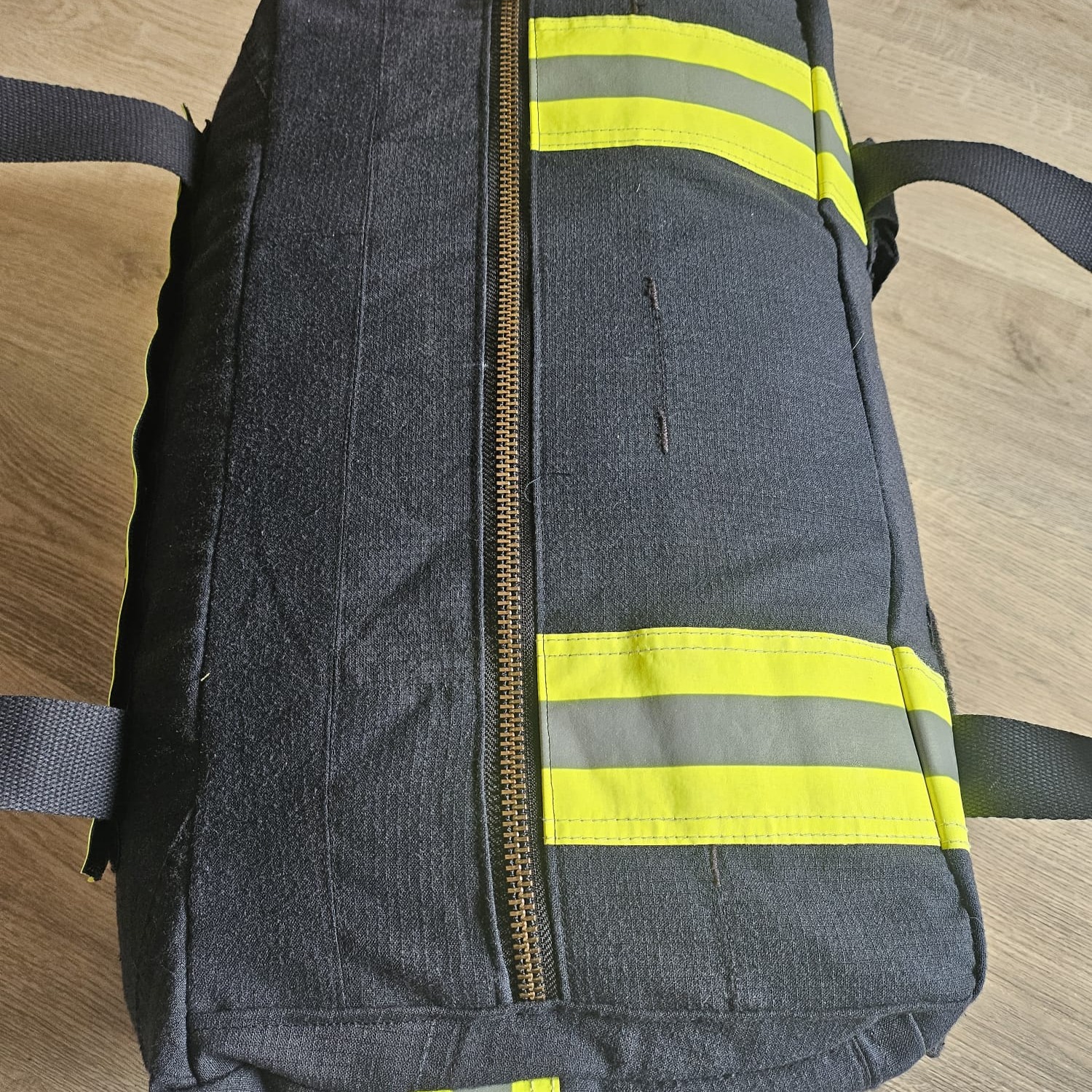 Draufsicht einer geschlossenen, dunkelblauen Feuerwehr-Tasche mit langem Metallreißverschluss, Reflexstreifen und Tragegriffen
