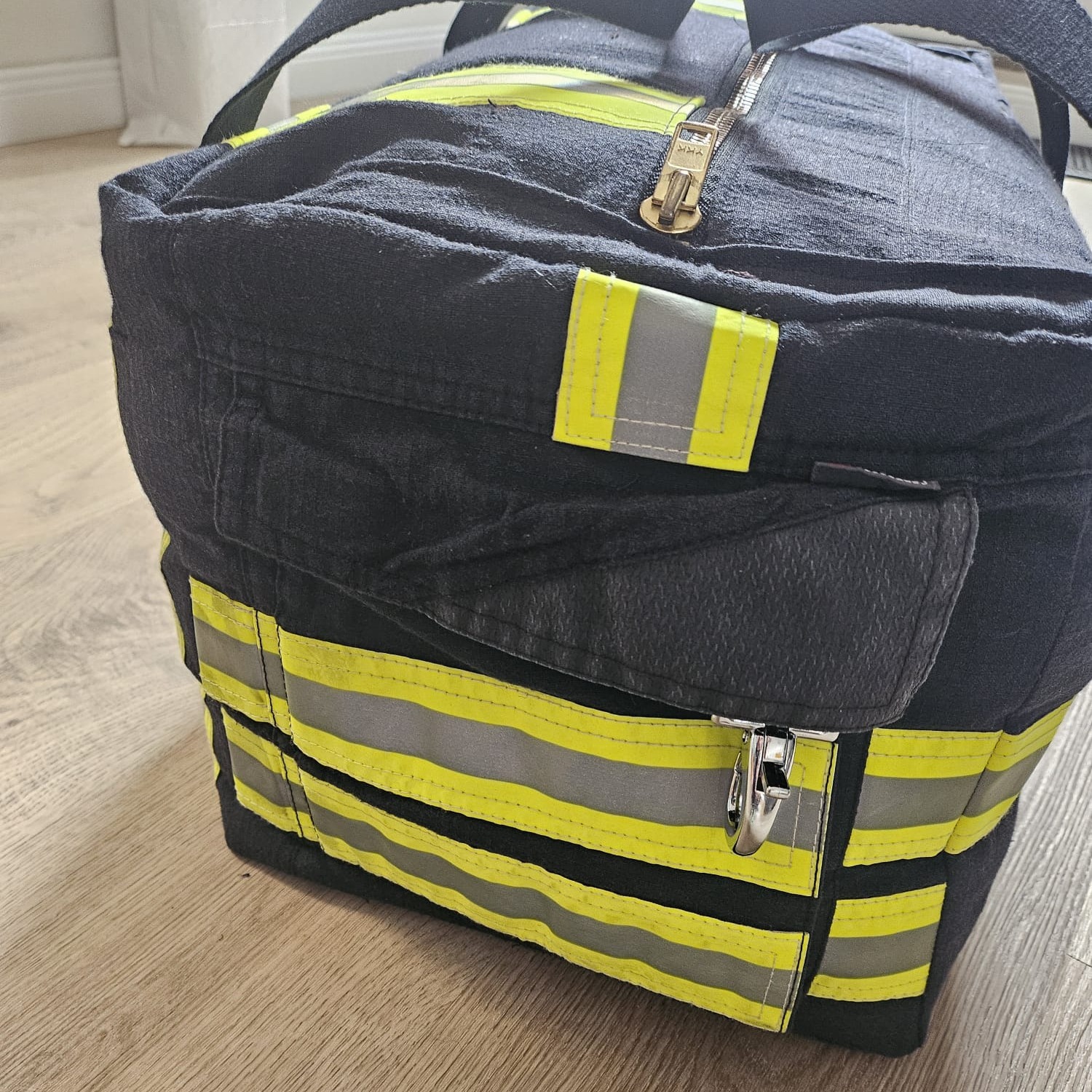 Dunkelblaue Feuerwehr-Tasche mit Fokus auf Karabinerverschluss, Reflexstreifen und YKK-Metallreißverschluss