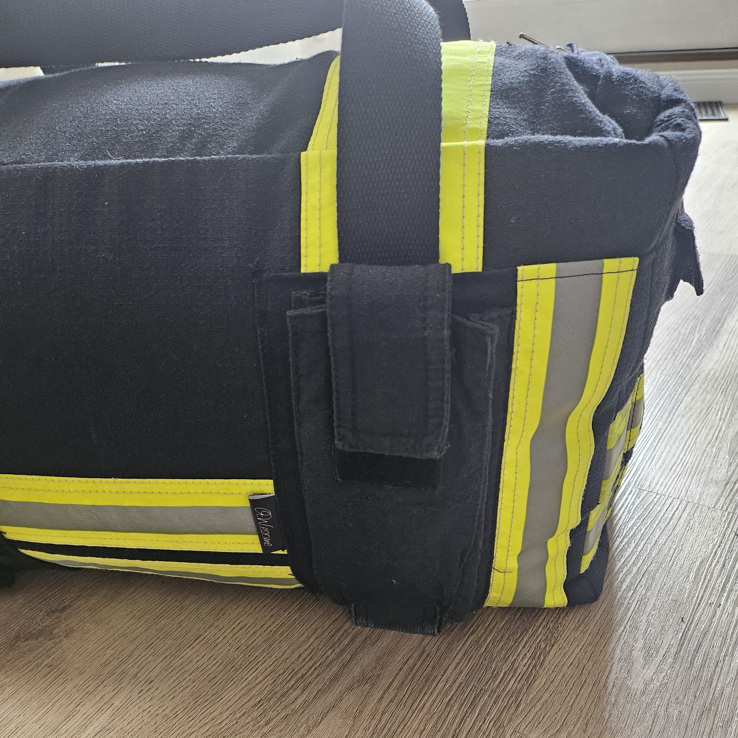 Dunkelblaue Feuerwehr-Tasche mit Tragegriffen, gelb-silbernen Reflexstreifen und einer geschlossenen Außentasche