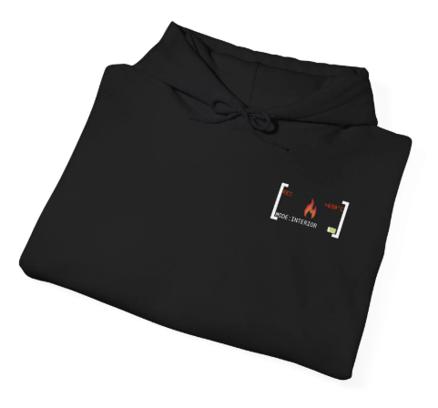 Zusammengelegter schwarzer Hoodie flach liegend vor weißem Hintergrund mit dem kleinen Brustlogo „MODE: INTERIOR“ im Wärmebildkamera-Stil.