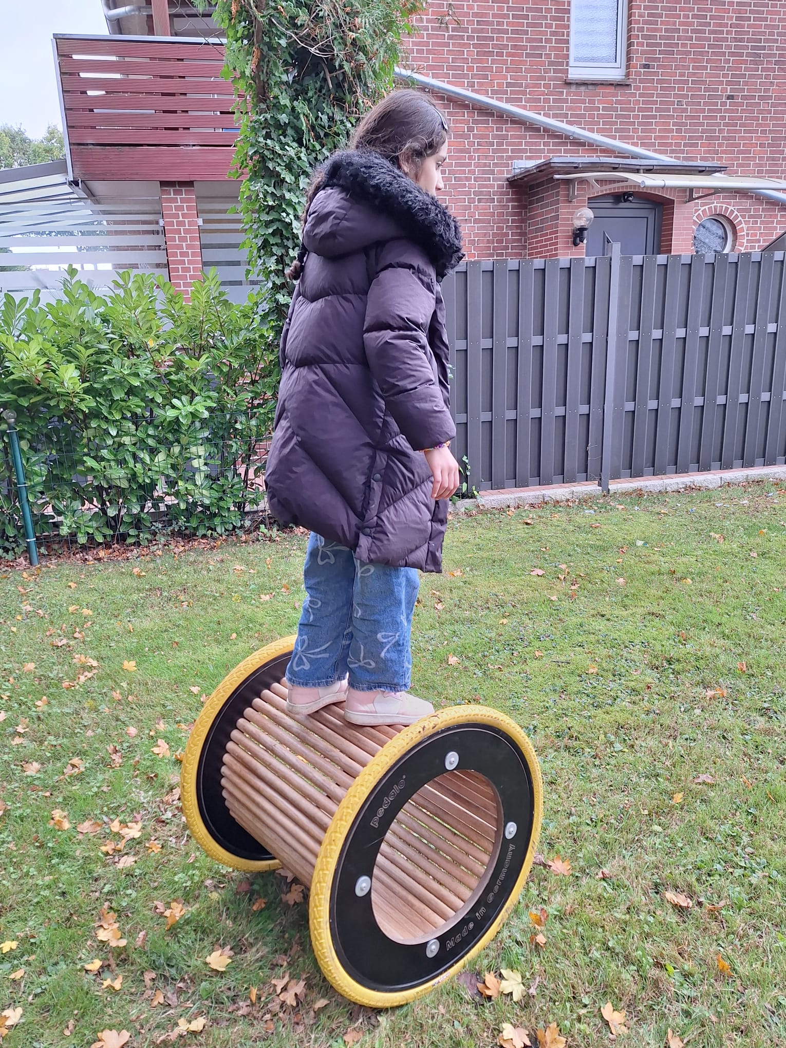 Ein Mädchen balanciert stehend auf einem runden Spielzeug.