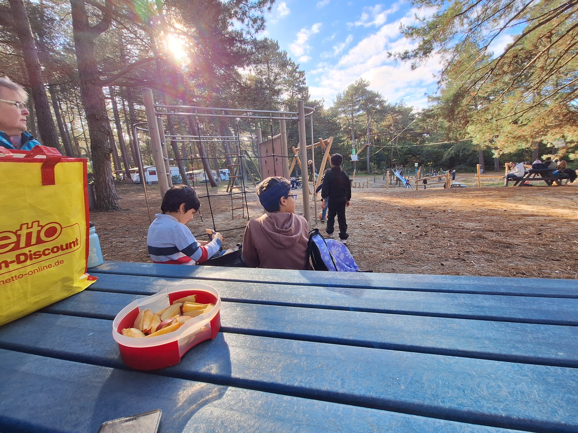 Kinder sitzen auf einer Picknickbank und essen.