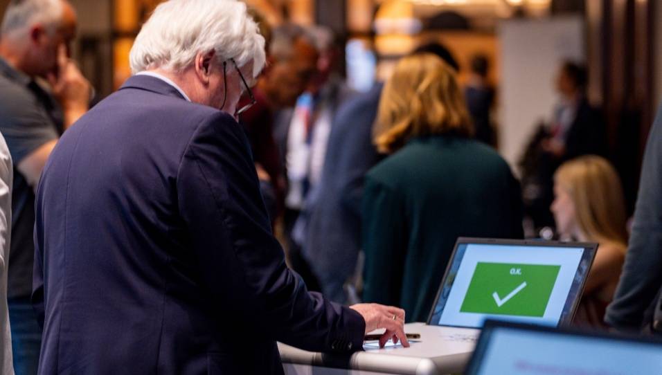 Eine Person steht vor einem SelfPrint Kiosk und scannt einen QR-Code auf dem Smartphone. Der SelfPrint-Kiosk zeigt einen grünen Bildschirm mit "Ok" an.