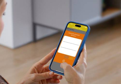 Auf dem Bild ist ein Smartphone zu sehen, welches von einer Person gehalten wird. Man schaut der Person über die Schulter zu. Auf dem Smartphone läuft eine App, die für ein Event gestaltet wurde.