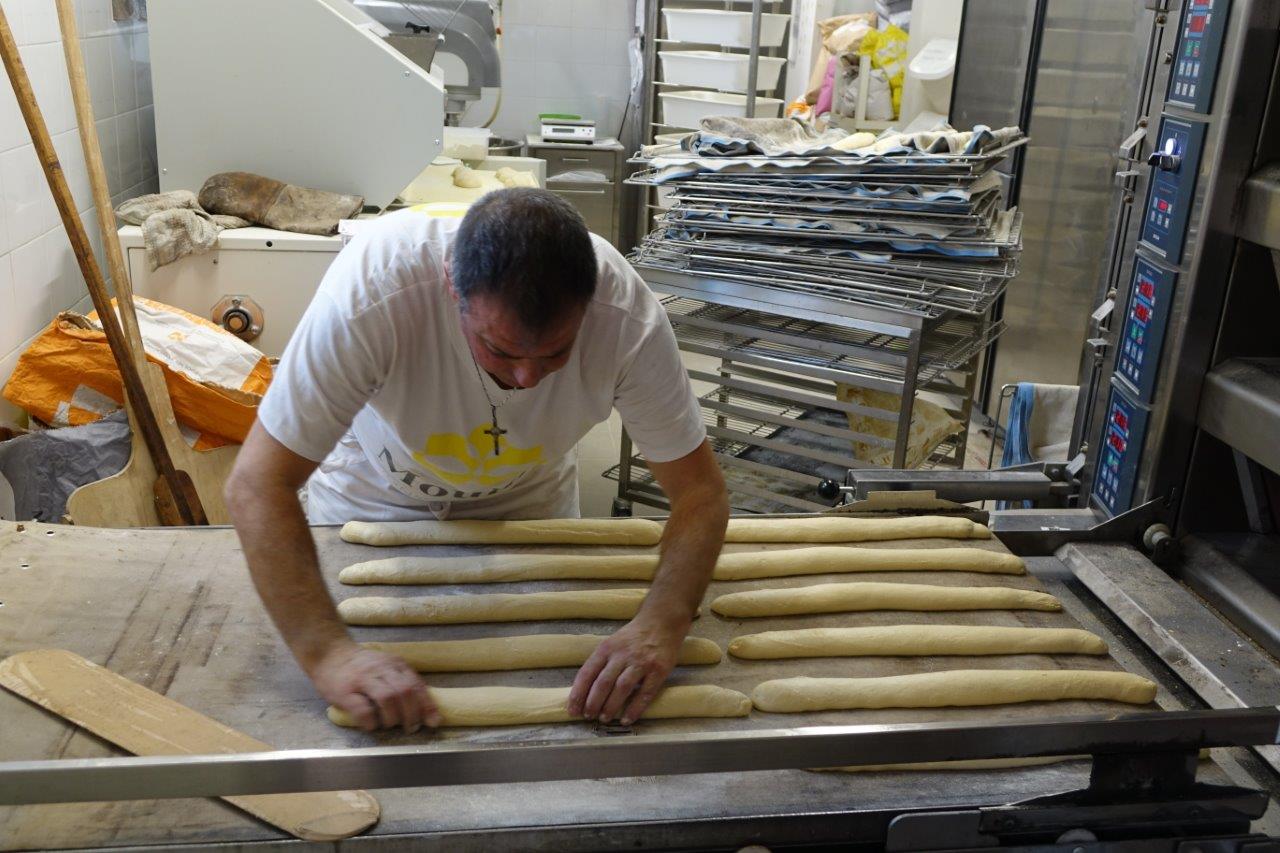 Dès la phase de fermentation terminée, le boulanger peaufine les baguettes avant d'enfourner.