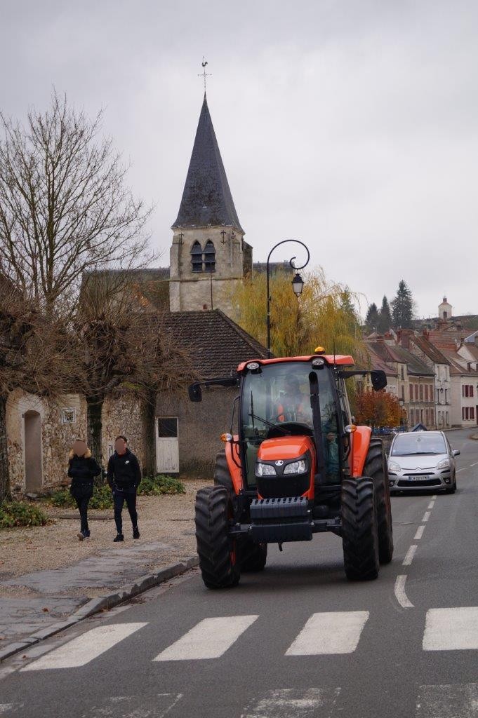 Le nouveau tracteur des employés municipaux se dirige vers la mairie pour l'arrosage.
