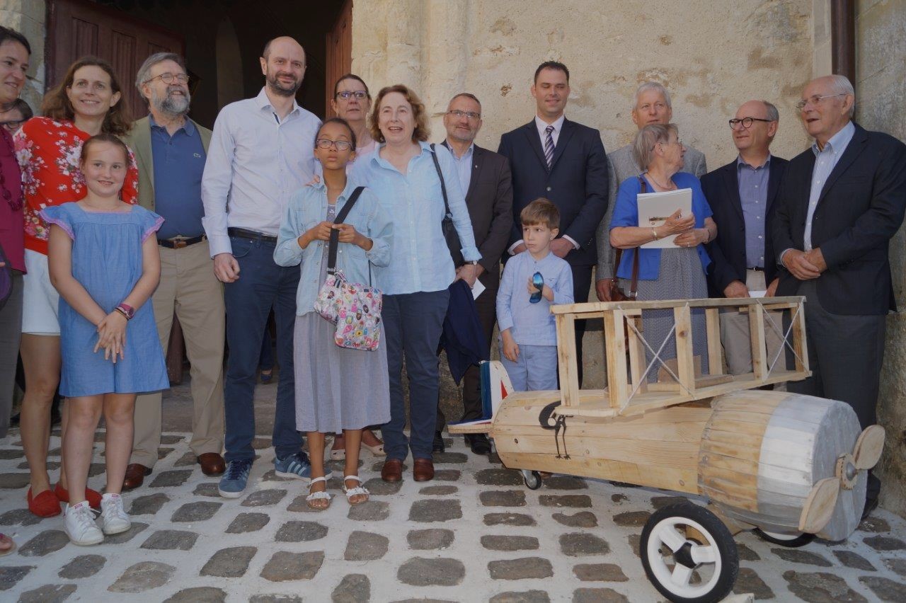 A la sortie de la messe, la famille de Xavier Moissinac et les élus posent près l'avion SPAD XIII construit en bois de palette par des bénévoles de la paroisse.