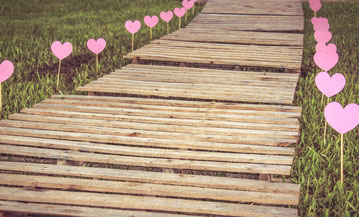 chemin en bois bordé de petits cœurs au milieu d’une prairie symbolisant le parcours d’une thérapie de couple à Rennes.