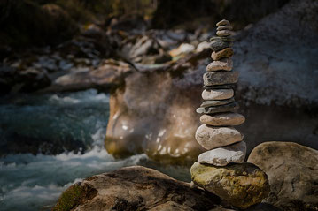 Pierres en équilibre au bord d’une rivière symbolisant l’équilibre intérieur que l’on peut retrouver grâce à une thérapie brève à Rennes ou à Bruz.