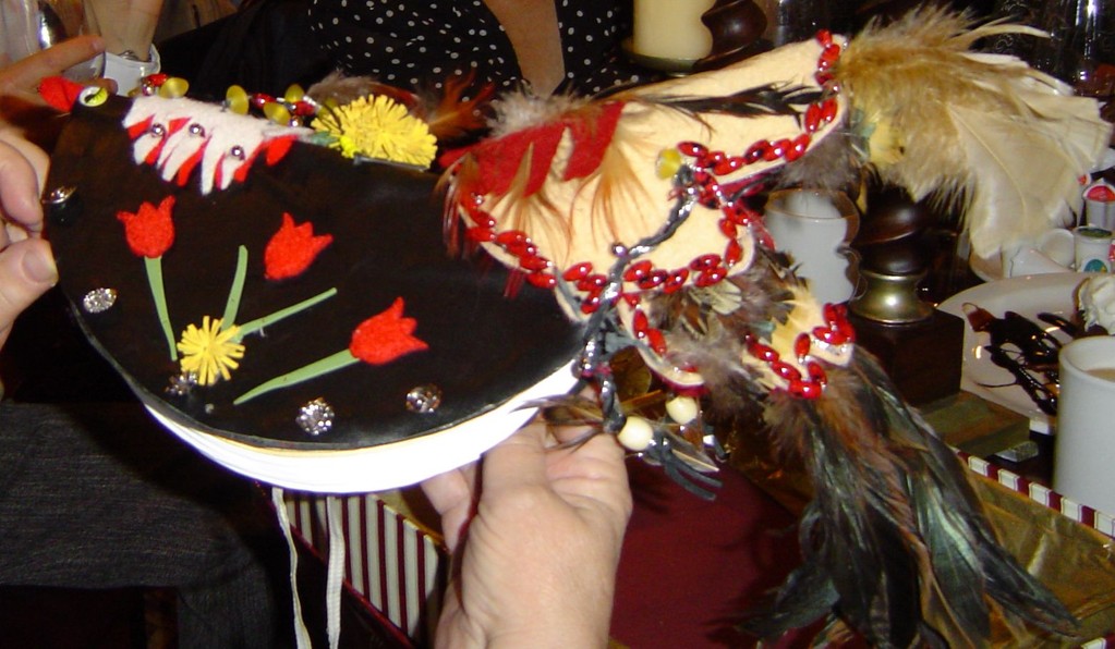 Carte en forme d'oiseau en cuir fabriquée avec des plumes pour la queue,                                                                                                                        des perles, des fleurs artificielles ainsi que de la feutrine.
