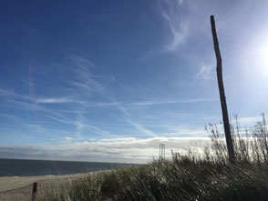 Ein blauer Himmel, Dünen und im Hintergrund die Nordsee. Ein Symbol für innere Ruhe, so wie es Psychotherapie in Gladbeck leisten kann.