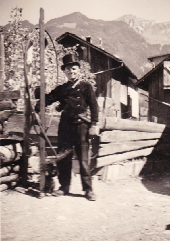 Archivbild: Der junge Hans Tschudi in "Berufsuniform" und mit den Kaminfegerutensilien, vermutlich im Dorfquartier "Loch", im Hintergrund der Obstock und Nüenchamm, Mollis. (Foto: Margrit Neeracher).