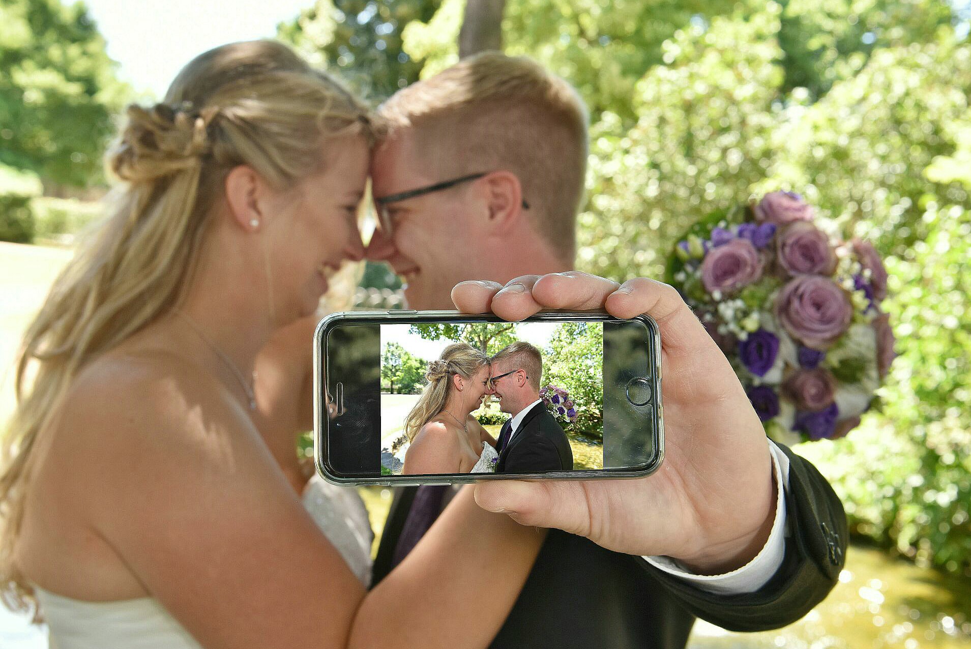Brautpaar fotografiert sich selbst mit dem Handy – moderner Hochzeitsmoment