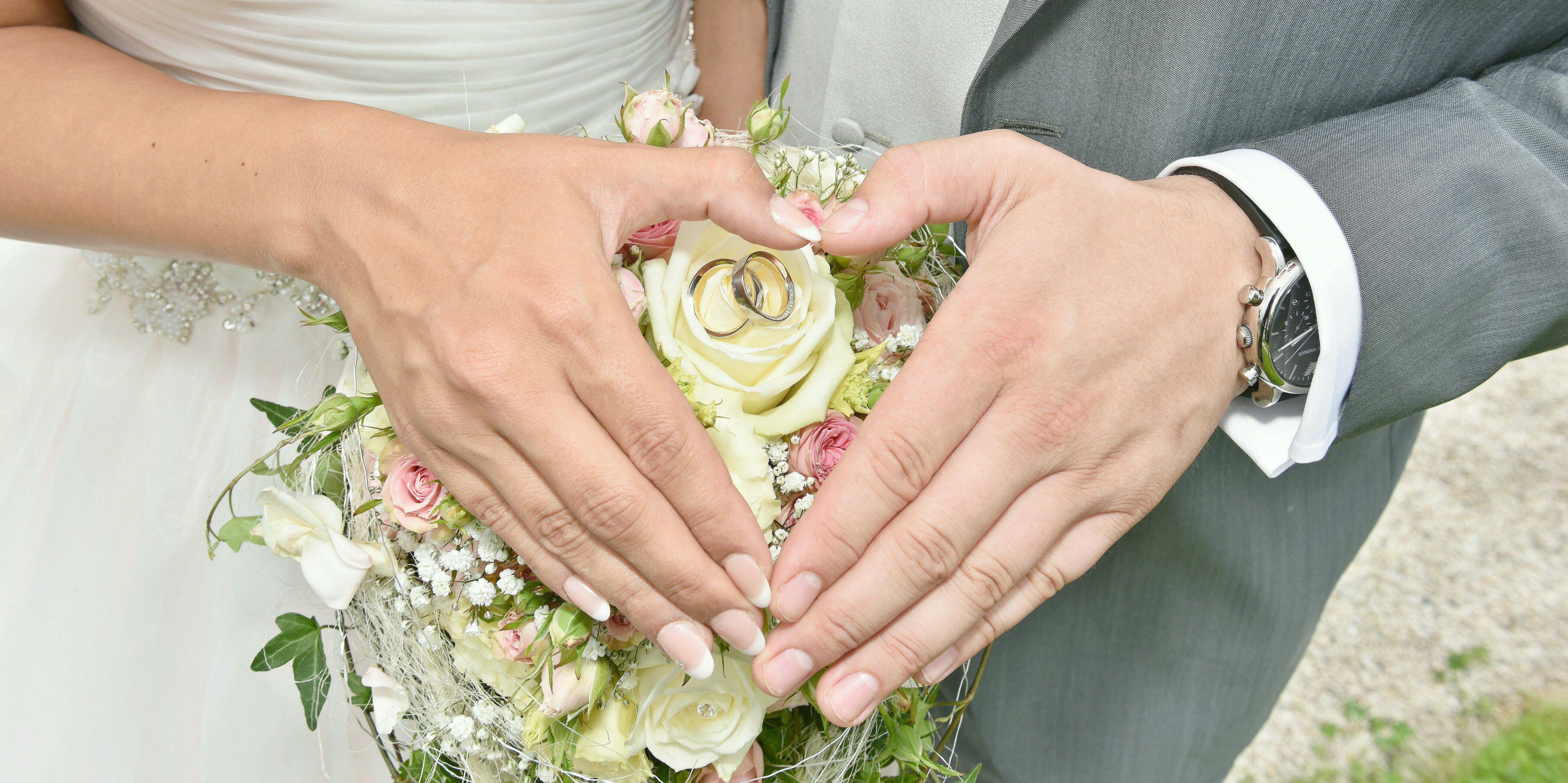 Hände Brautpaar mit Strauß und Ringen