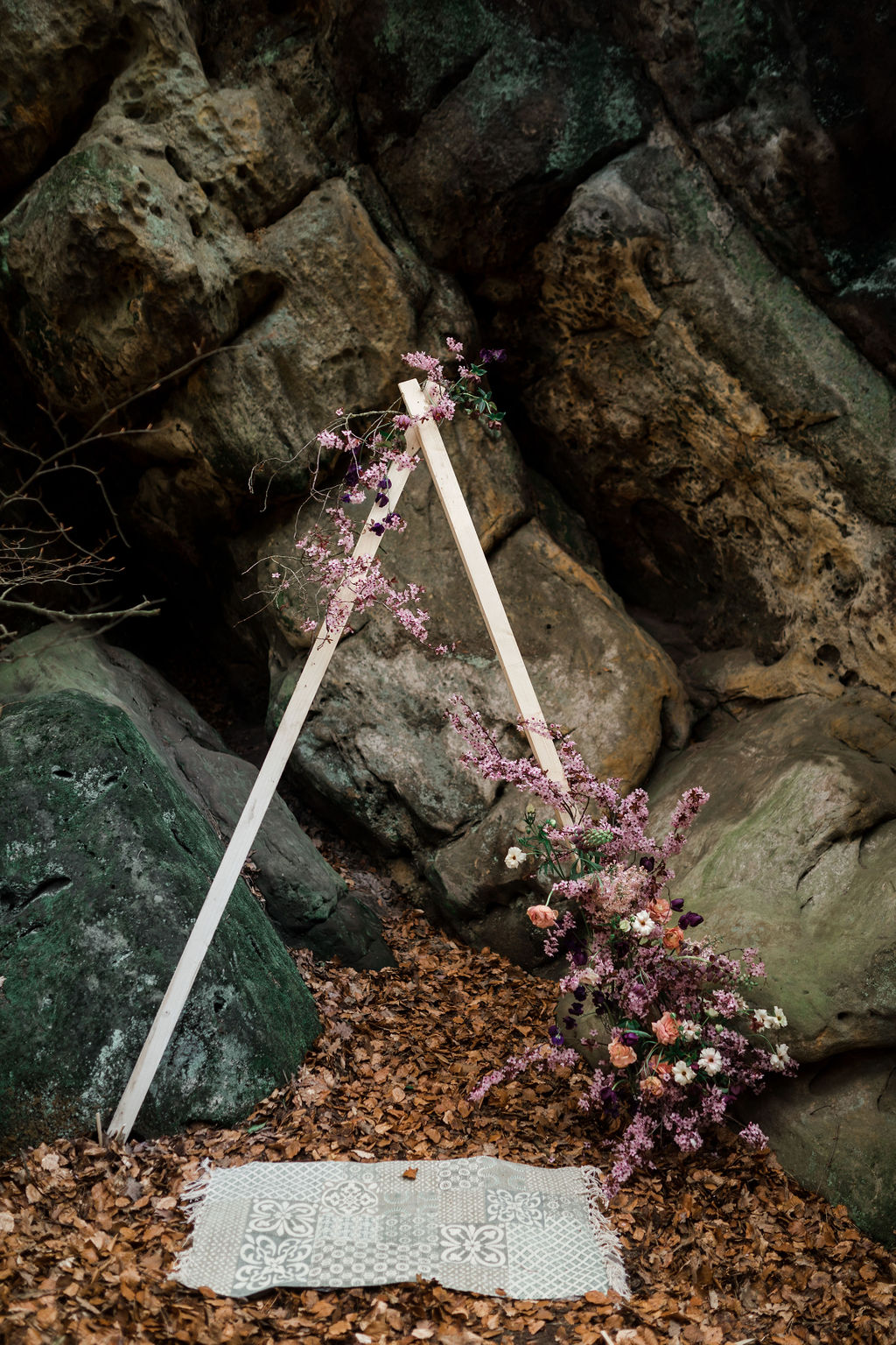 Traubogen mit Blumendekoration vor Felsen, Teppich