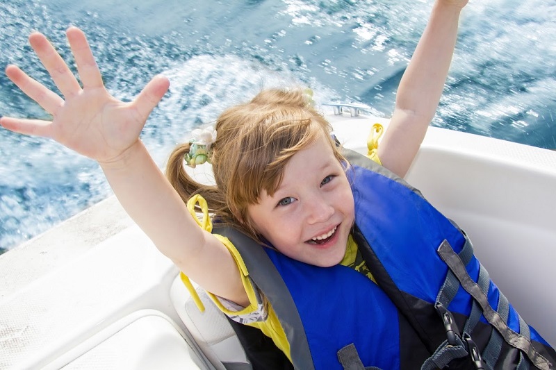 happy little girl on the boat wearing life vest
