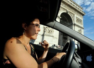 En voiture sur la Place de l'Etoile à Paris, avec l'Arc de Triomphe dans le fond