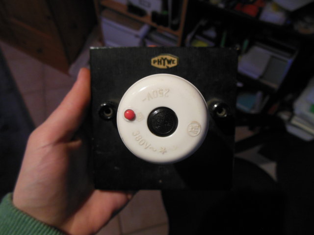 Löst man den Automat mit dem roten Knopf aus, so springt der schwarze hinaus und muß wieder hineingedrückt werden, will man wieder Strom haben.