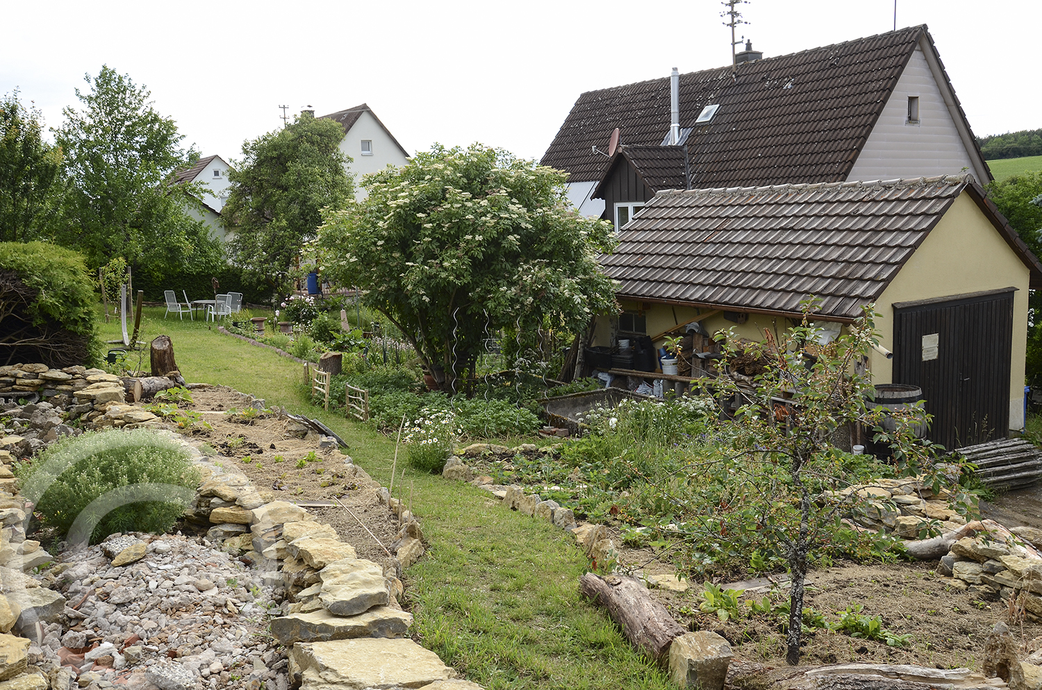 Warten auf die Kieslieferung. In diesem Naturgarten wachsen Wildblumen und Gemüsepflanzen nebeneinander.
