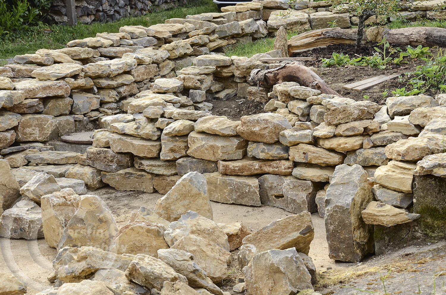 Es sind noch Steine übrig. Deshalb wurde vor dem Gemüsebeet unplanmäßig eine weitere Trockenmmauer gebaut. Dort soll ein Glockenblumenbeet entstehen.